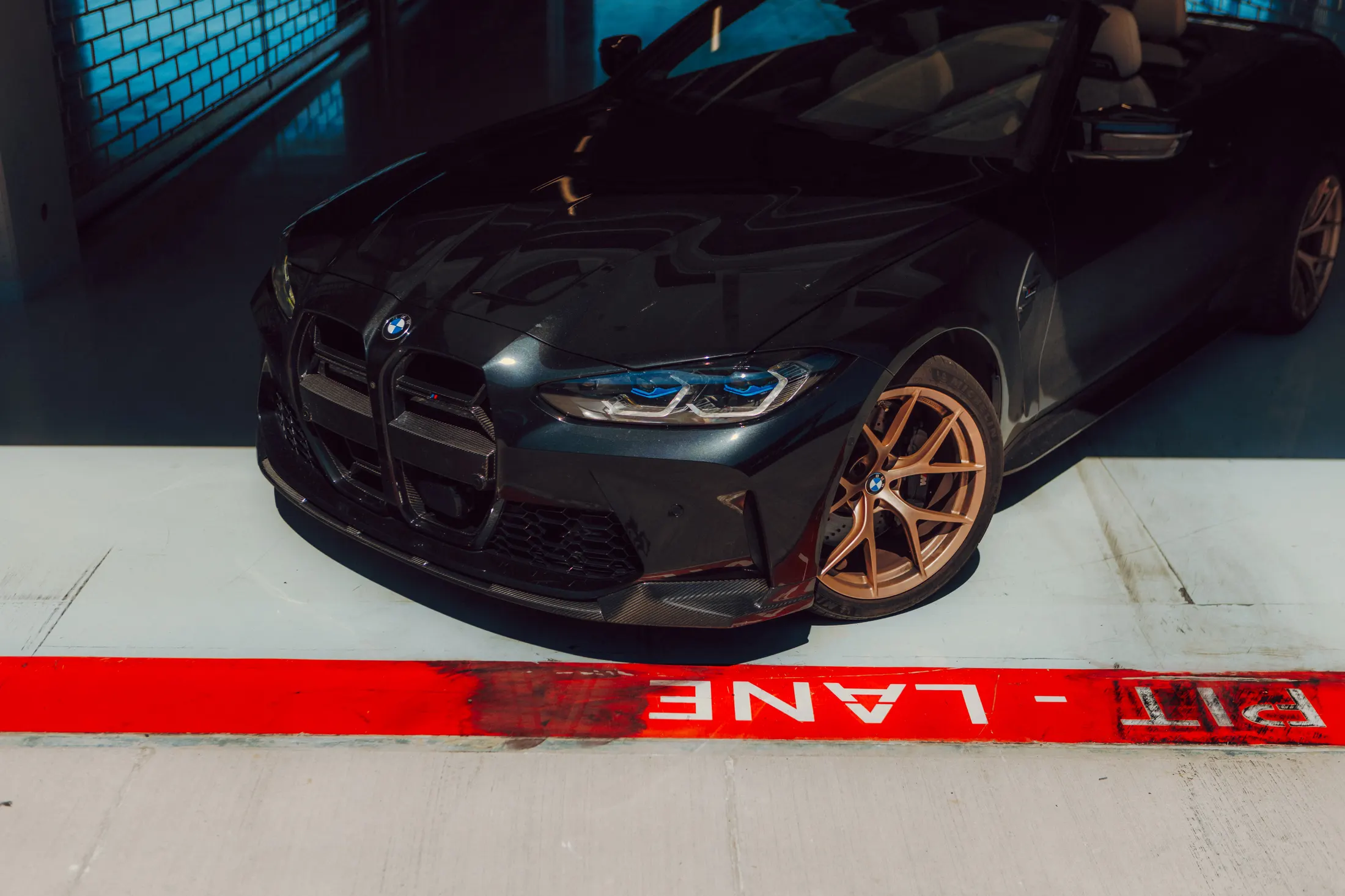 Fekete BMW M4 Competition bronz felnikkel a pit lane piros vonalánál